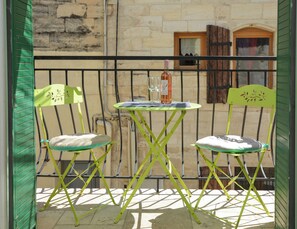 A balcony with two green chairs and a small table, a bottle of wine, and a glass. - Charming Renovated Two-Person House in the Heart of Beaucaire (Beaucaire)