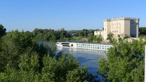 A castle by a river with a boat docked nearby. - Charming Renovated Two-Person House in the Heart of Beaucaire (Beaucaire)