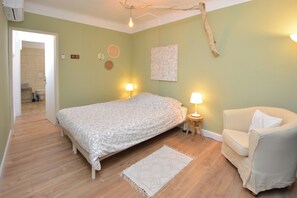 A bedroom with a bed, a chair, a lamp, and a wall decoration. - Charming Renovated Two-Person House in the Heart of Beaucaire (Beaucaire)