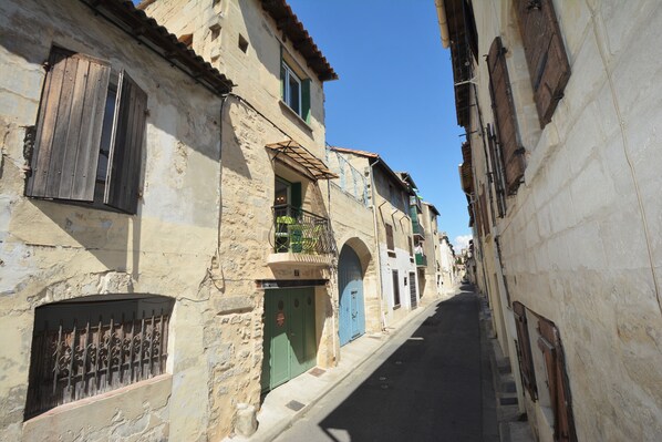 Une rue étroite bordée de bâtiments en pierre, de volets en bois et surplombée d’un ciel d’un bleu éclatant.
