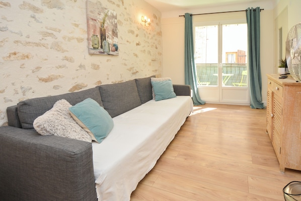 Une pièce avec un canapé gris, un meuble en bois et un balcon avec vue.