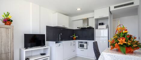 A modern kitchen with white cabinetry, a built-in microwave, and a dining area with a table set for two.