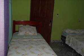 A small room with two single beds, a wooden door, and green walls. - Hotel Del Rio (Carolina)
