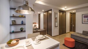 A modern living room with a dining area, featuring a table set with plates and cups, a sofa, and a red ottoman. - ZITU 106 (Bogotá)