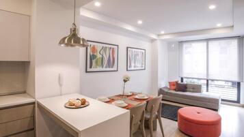 Un apartamento moderno con comedor, sofá y un amplio ventanal.