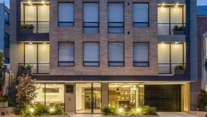 A modern multi-story building with a flat roof, large windows, and a well-lit entrance. - ZITU 106 (Bogotá)