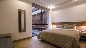 A modern bedroom with a large bed, a nightstand, a mirror, and a window with a view of a wooden structure outside. - ZITU 106 (Bogotá)