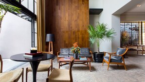 A spacious living area with a wooden accent wall, a round table with chairs, a sofa, and a coffee table. - Casa 9 (Mexico City)