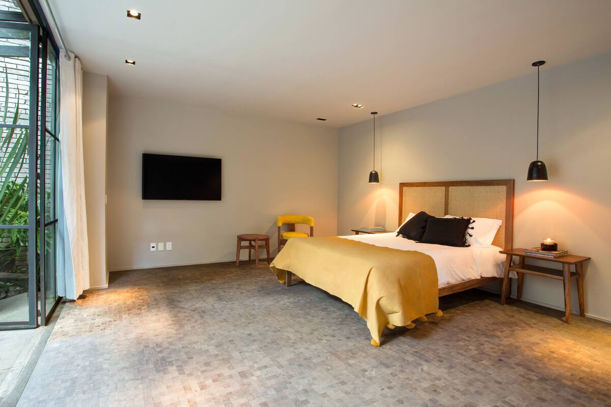 A modern bedroom with a bed, bedside tables, a TV, and a window.