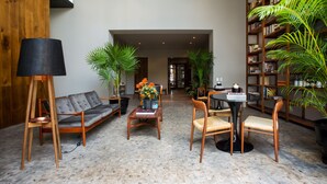 A spacious lobby with a modern sofa, a coffee table, and a bookshelf filled with books. - Casa 9 (Mexico City)