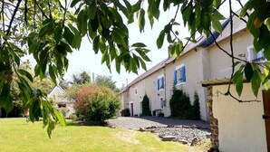 Il s’agit d’une propriété résidentielle dotée d’une pelouse bien entretenue, d’un chemin en pierre et d’une maison avec un toit en tuiles et des volets bleus.