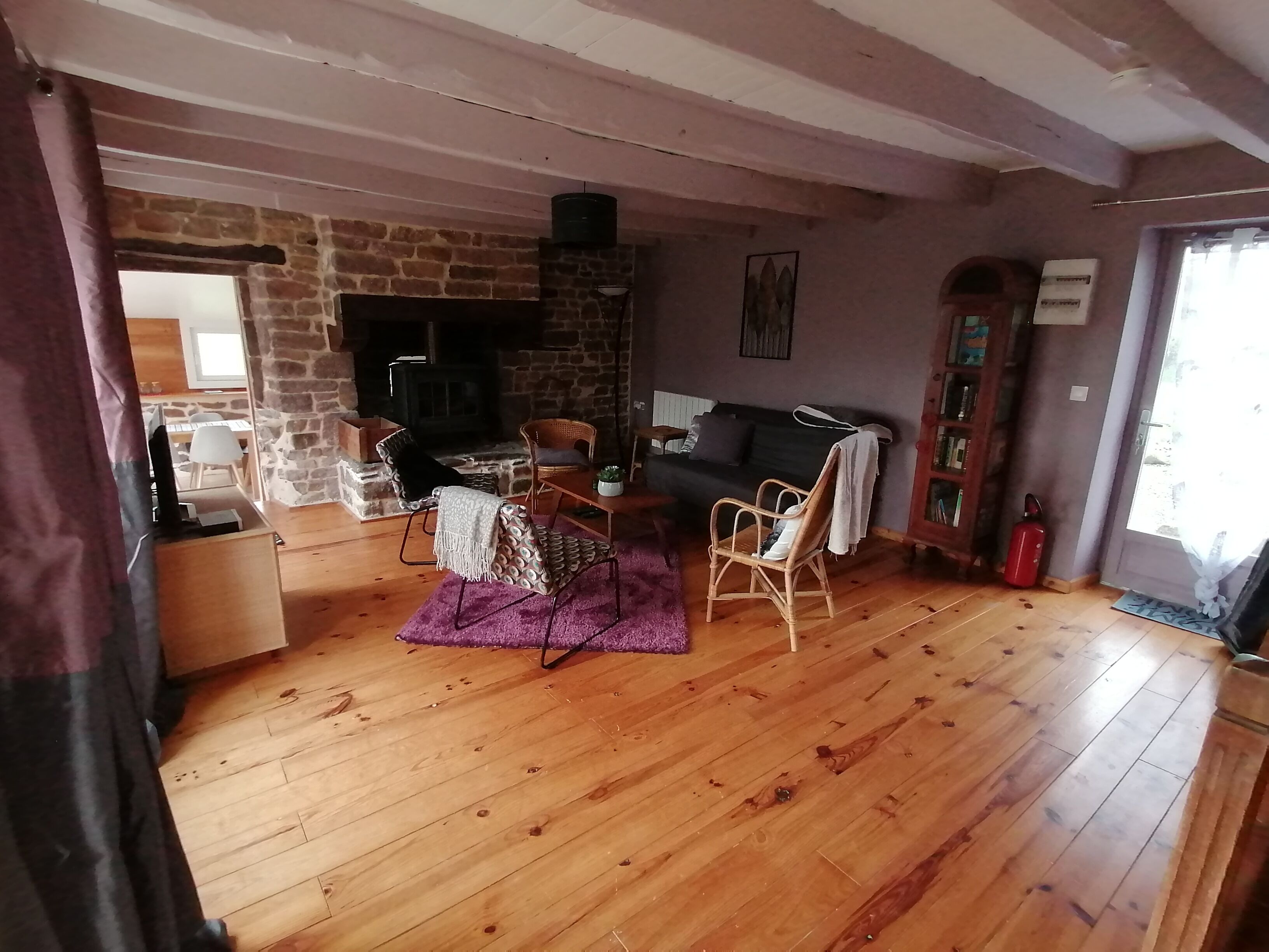 Una sala de estar con chimenea de piedra, piso de madera, un sofá y un comedor.