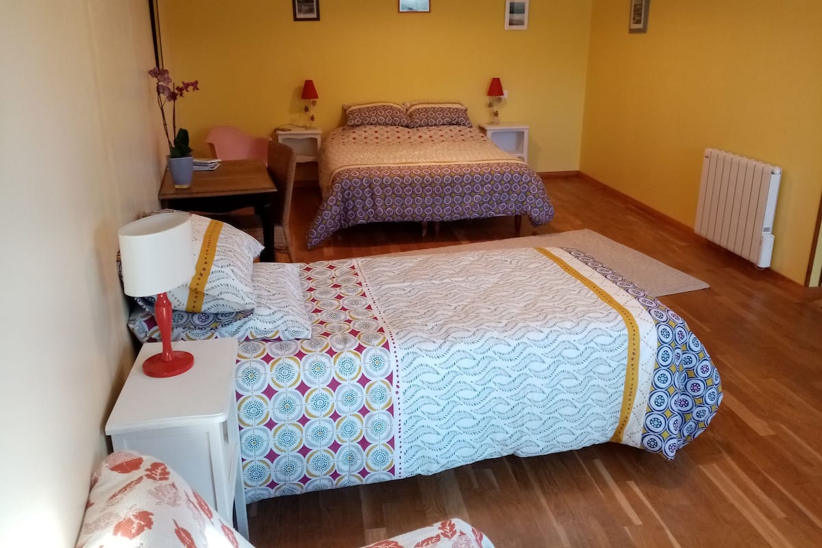 A bedroom with a bed, a desk, a chair, a lamp, and a radiator.