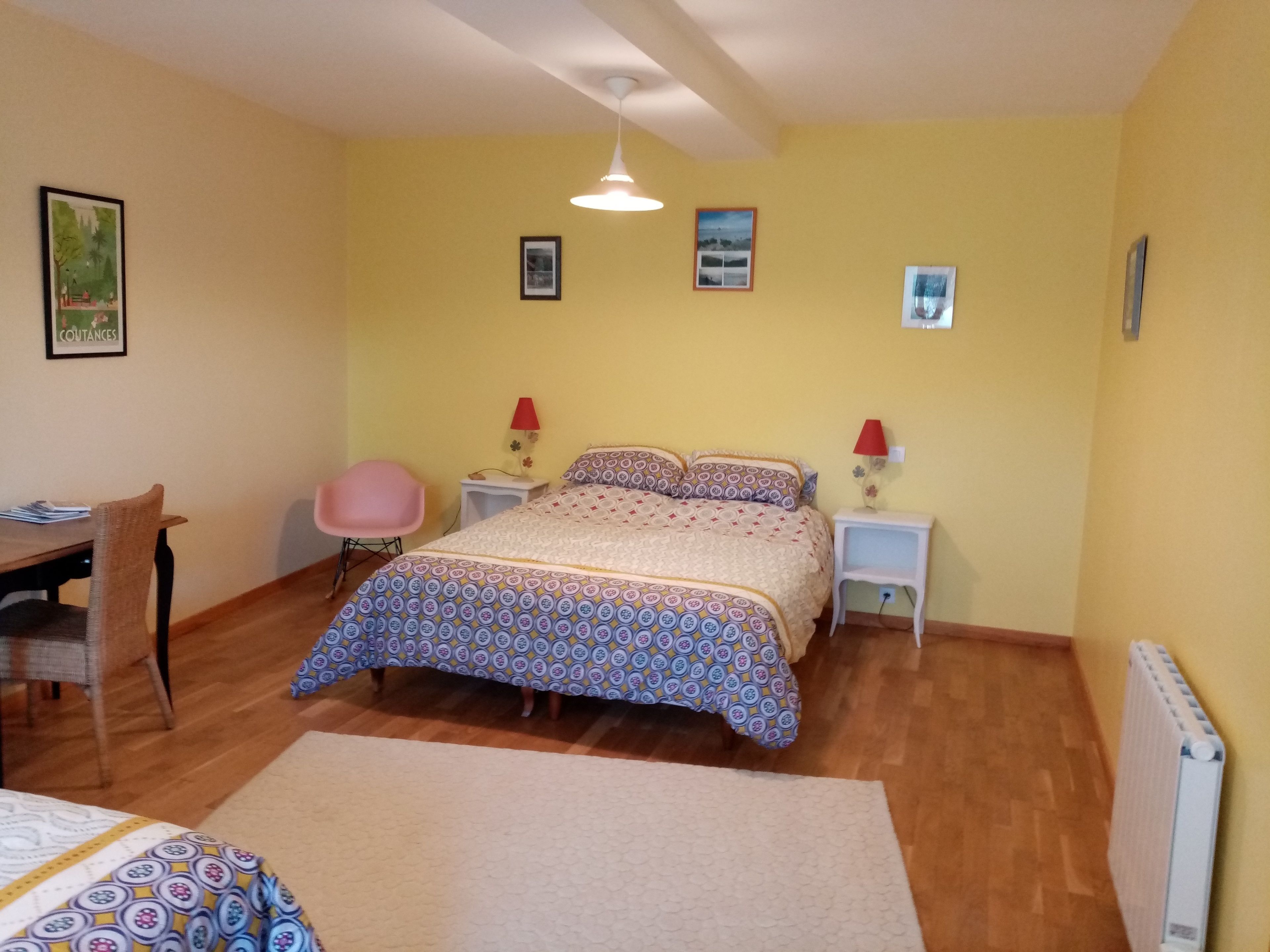 A bedroom with a bed, two bedside tables with lamps, a chair, a desk, and a radiator.