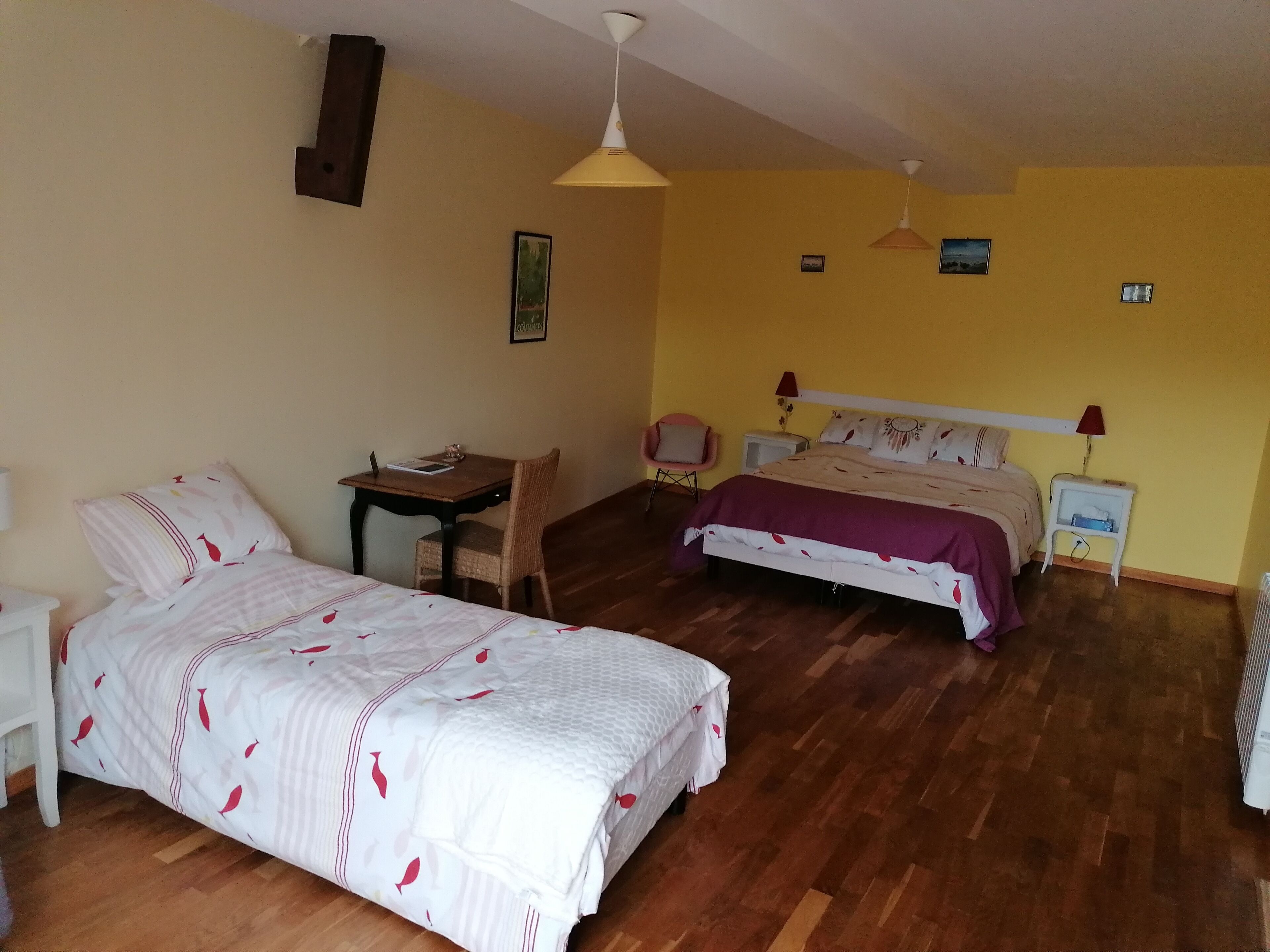 A bedroom with two beds, a desk, a chair, and a small table.