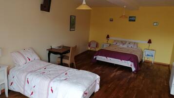 A bedroom with two beds, a desk, a chair, and a small table.