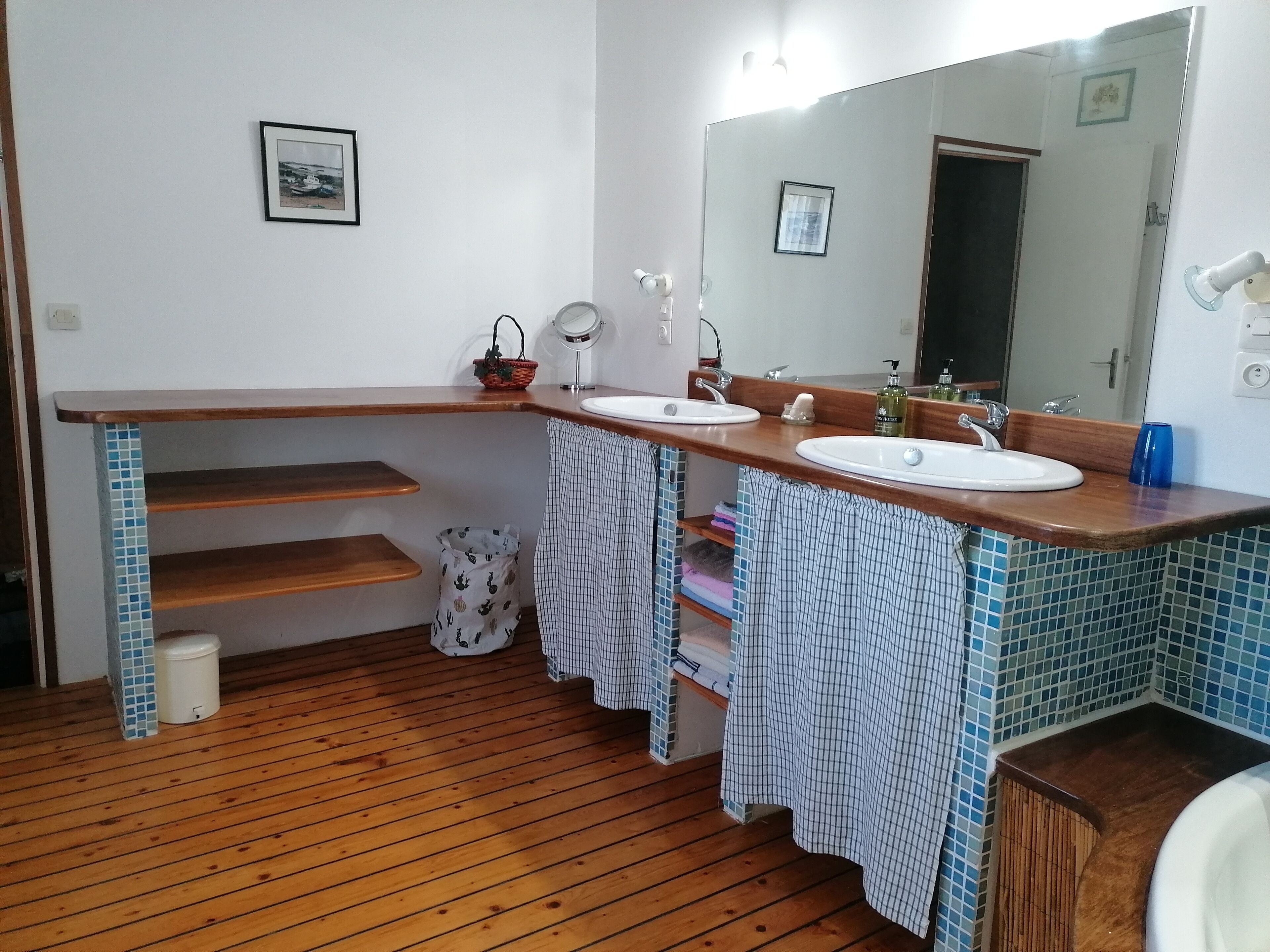 Une salle de bain avec deux lavabos, un miroir et un plancher en bois.