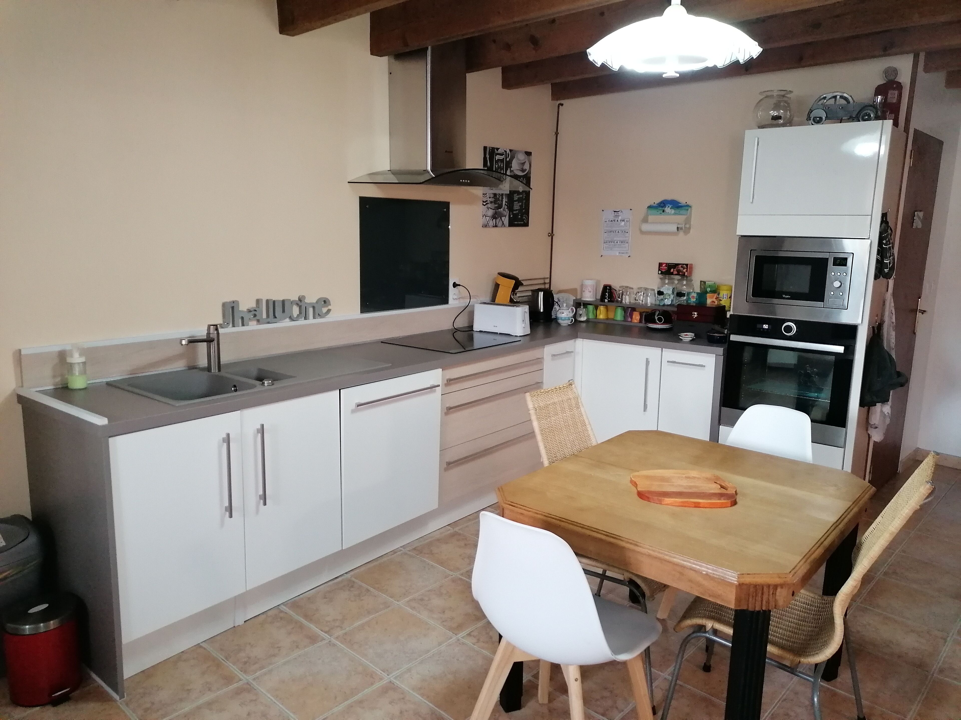 A compact kitchen with a sink, stove, microwave, and a dining area with a table and chairs.