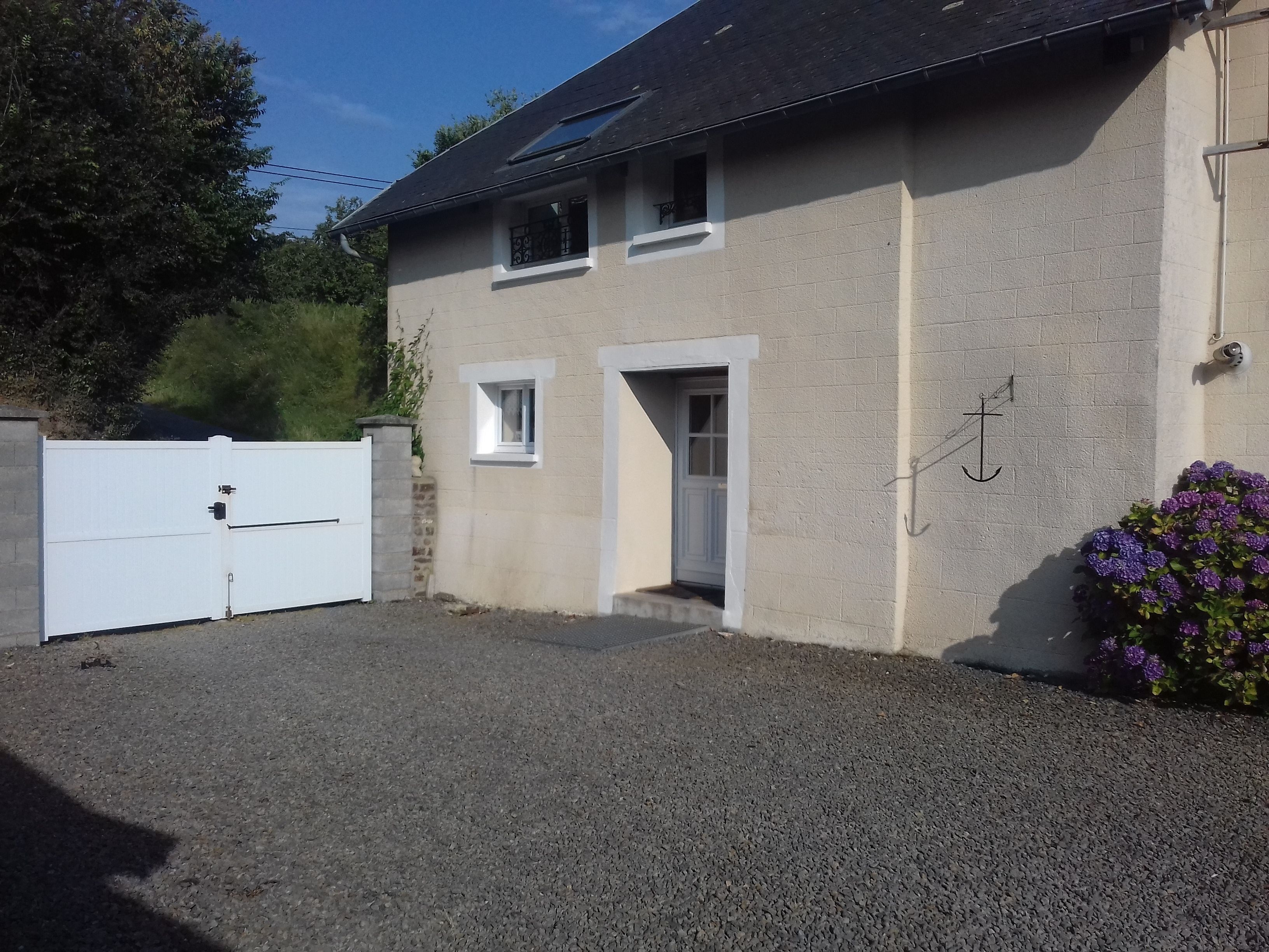 A two-story building with a white exterior, a gravel driveway, and a white gate.