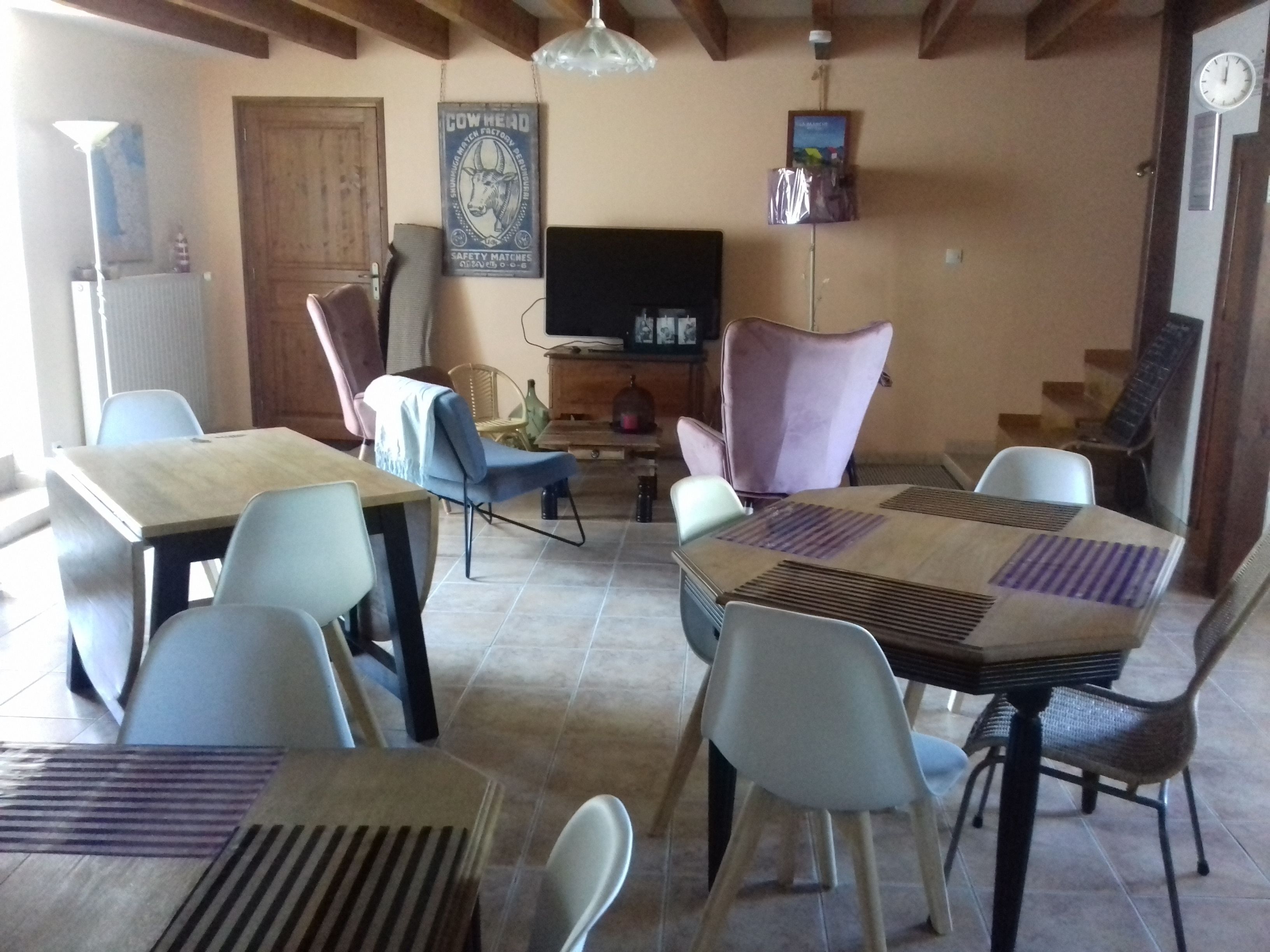 A dining area with a table and chairs, a television, and a clock on the wall.