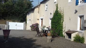A building with a gravel driveway, a wooden table with chairs, and a potted plant.