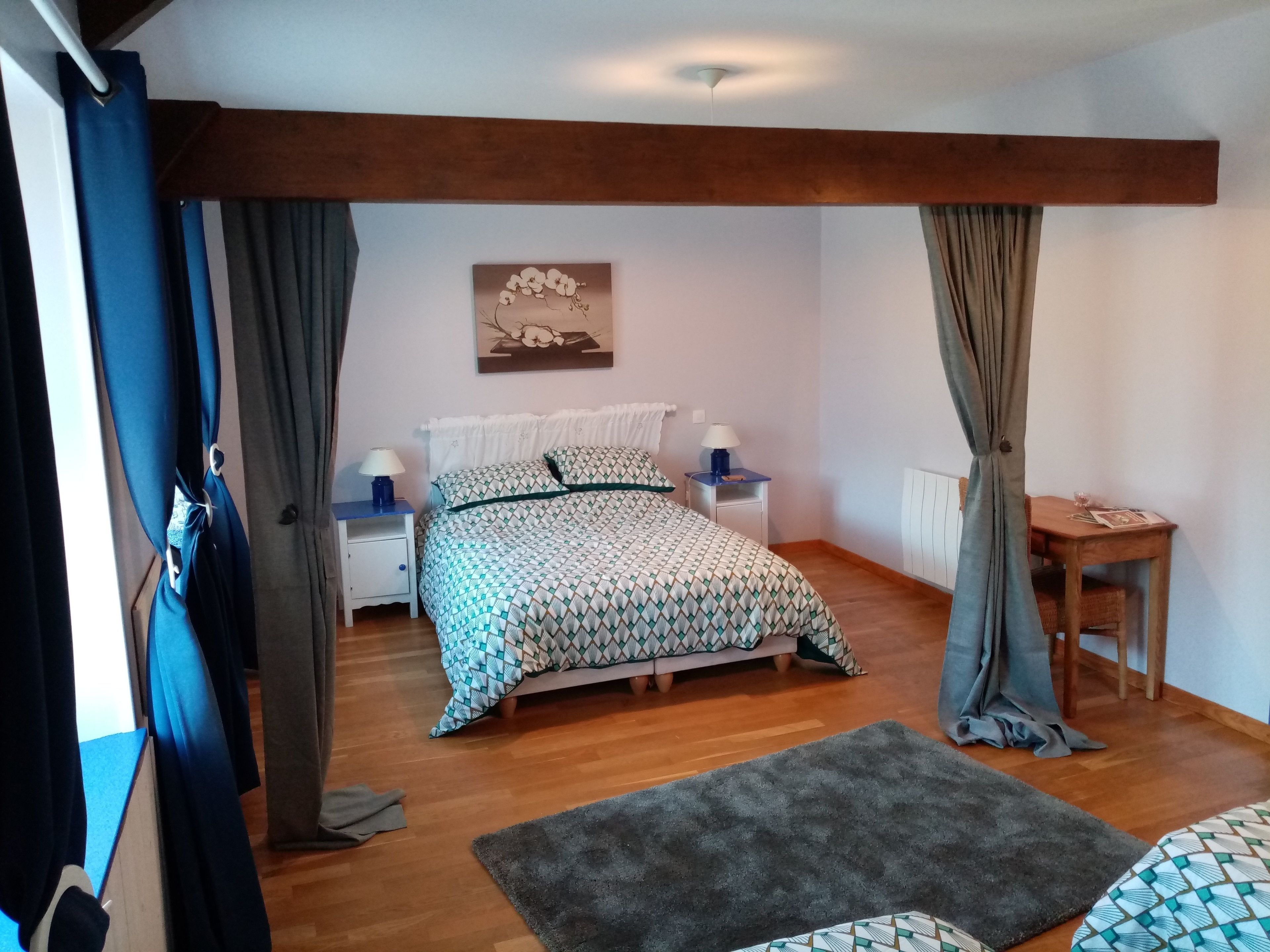 A bedroom with a bed, two bedside tables, a nightstand, a small table, and a chair.