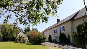 Un bâtiment doté d’un toit en pente, entouré d’une pelouse bien entretenue et d’arbres.