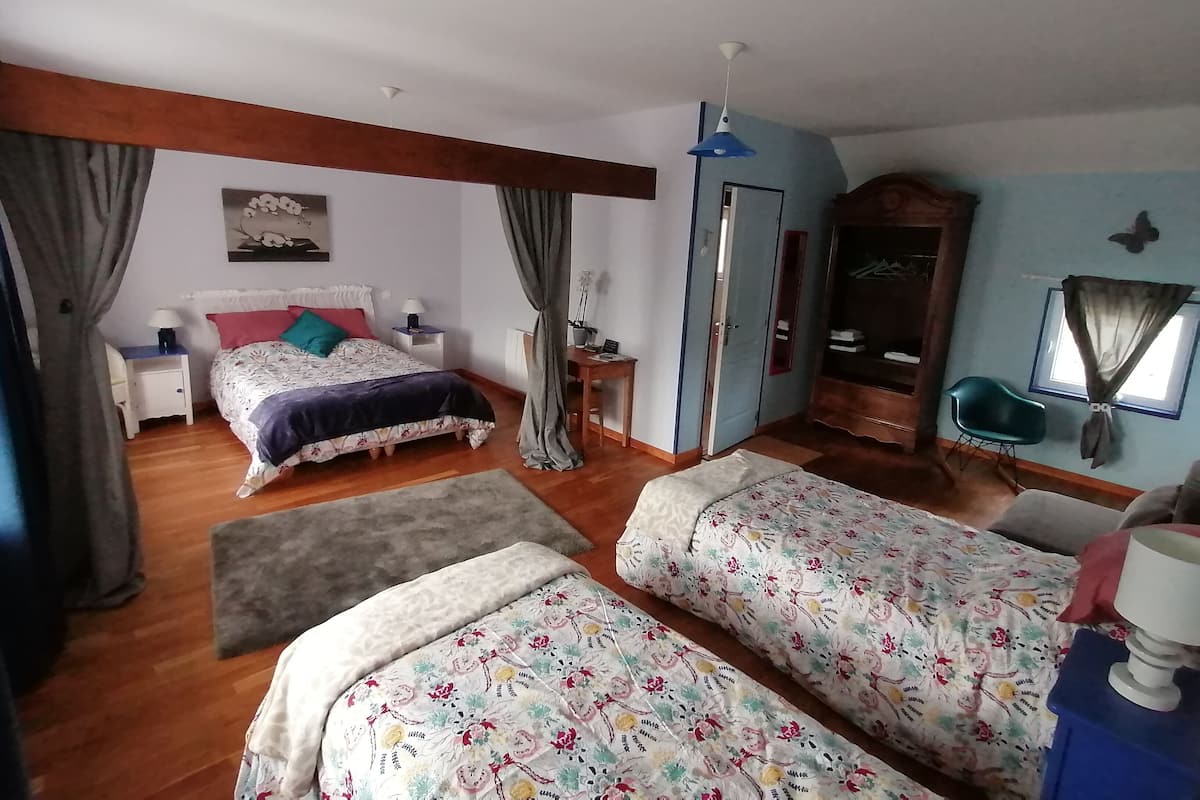 A bedroom with a bed, two bedside tables, a wardrobe, a mirror, and a window with curtains.