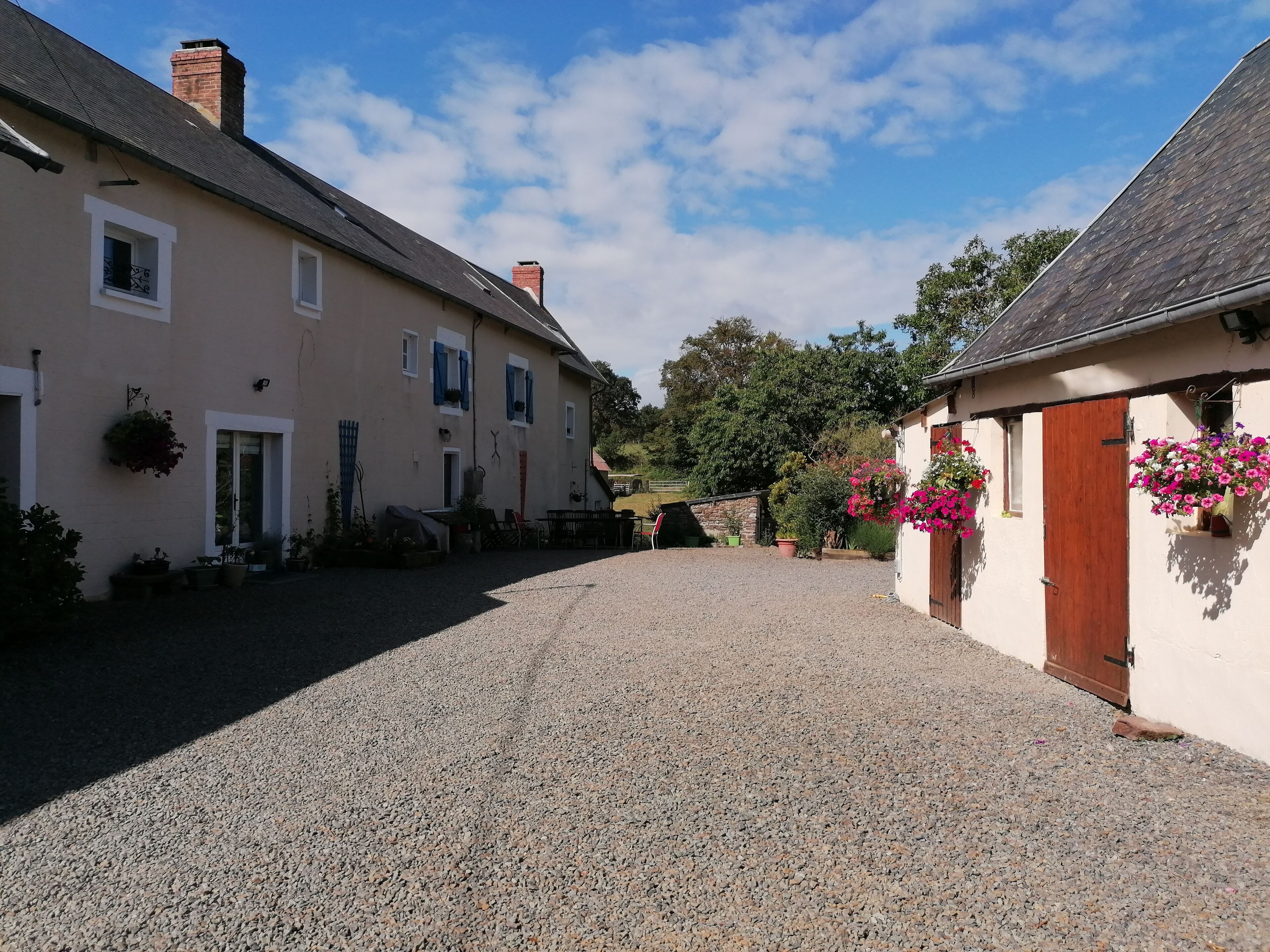 A gravel driveway leading to a row of buildings with a clear sky above.