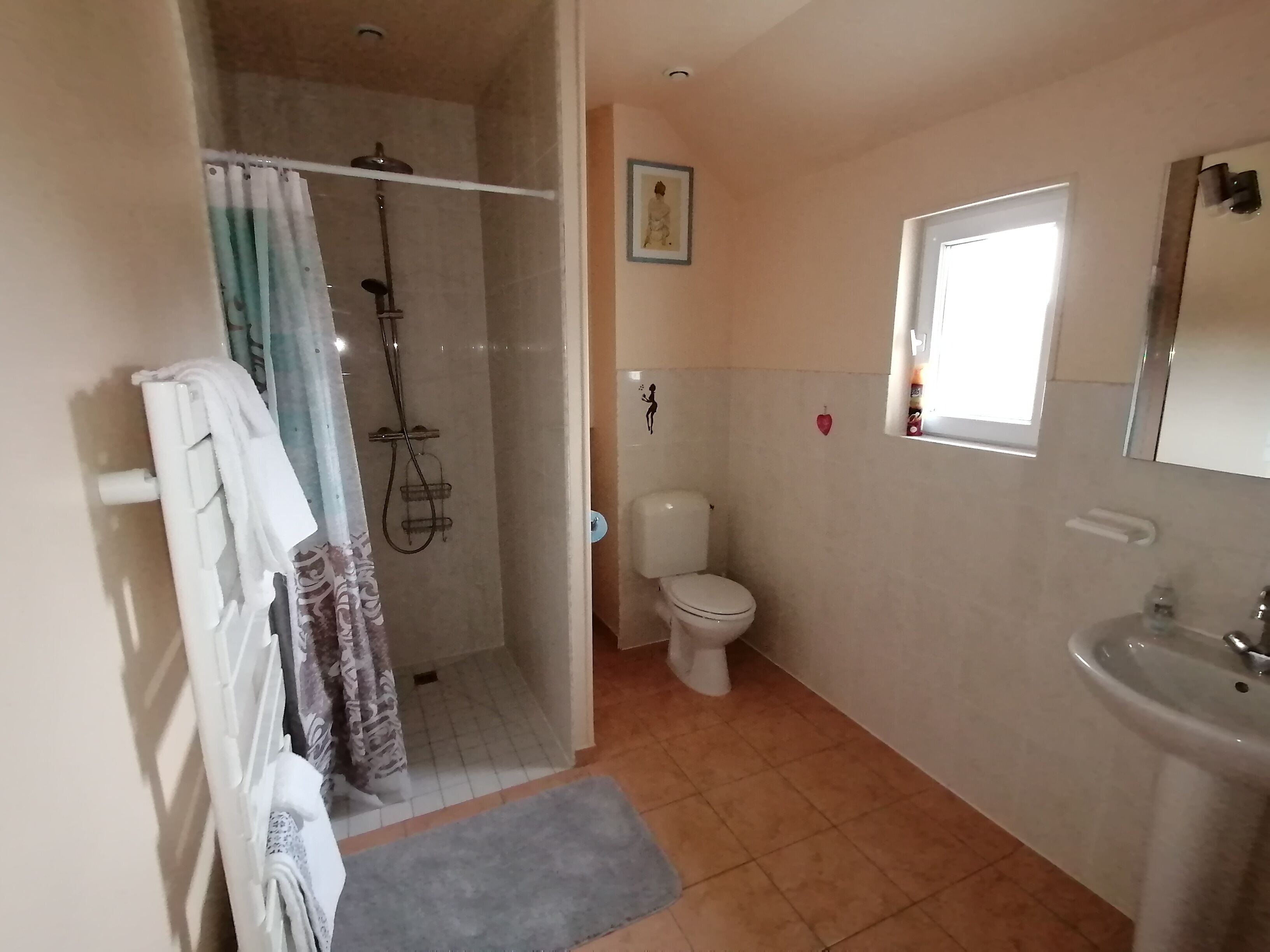 Un baño con ducha, inodoro, lavabo y una pequeña ventana.