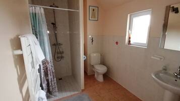 Un baño con ducha, inodoro, lavabo y una pequeña ventana.