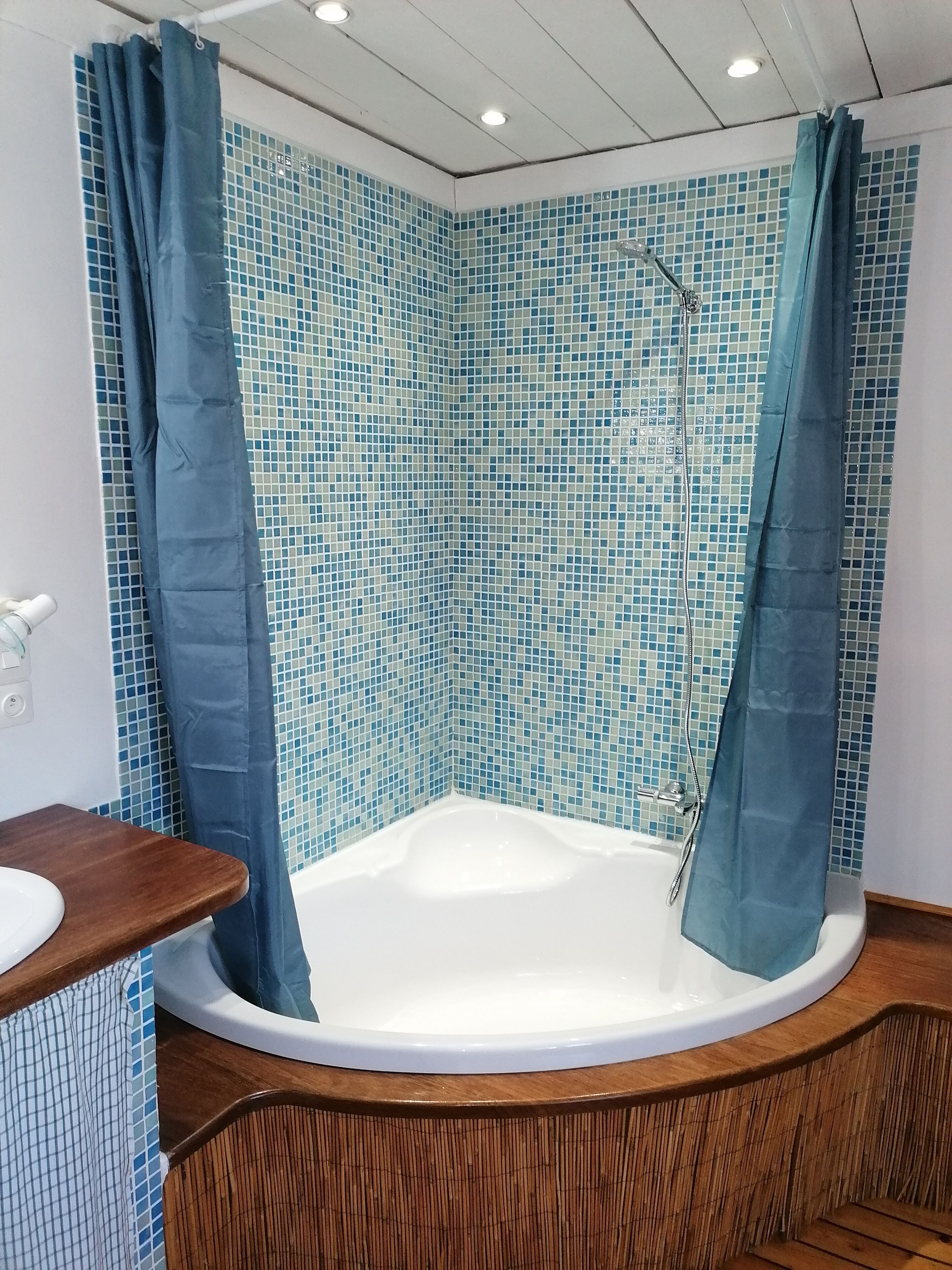 A bathroom with a bathtub, a wooden vanity, and a shower curtain.