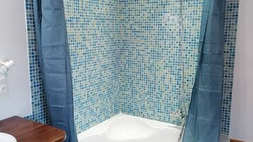 A bathroom with a bathtub, a wooden vanity, and a shower curtain.
