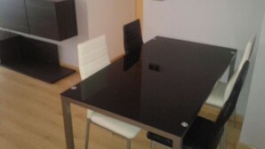 Una habitación con una mesa de madera oscura, sillas blancas y un banco blanco.