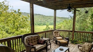 A wooden deck with wicker furniture, including a sofa and armchairs, and a glass-top table.