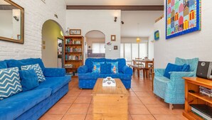 A living room with a blue sofa, a wooden coffee table, and a bookshelf. - Oceanside 20 - Sapphire (Boomerang Beach)