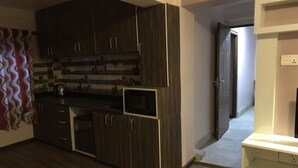 Een keuken met donkerhouten kastjes, een magnetron en een aanrecht.