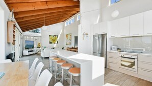 Een moderne keuken met witte kasten, een roestvrijstalen koelkast en een bar met krukken.