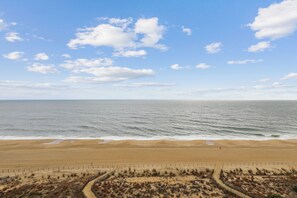 Una playa con una valla, dunas arenosas y el océano.