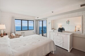 Une chambre d’hôtel avec un grand lit, une commode, un miroir et une vue sur la mer.