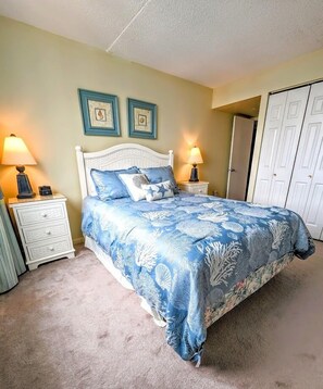 A bedroom with a bed, two nightstands, a wardrobe, and two wall-mounted pictures.