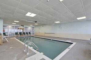 A swimming pool with a tiled deck, a lifeguard chair, and a pool ladder.