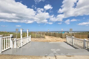 A beach access walkway with white railings and a concrete path leading to the shore.