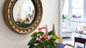 A room with a round mirror on the wall, a potted plant, and a window with curtains. - MORNING CHECK-IN IS GIVEN WHEN POSSIBLE -3BEDROOMS/2BATHS KNIGHTSBRIDGE (LONDON)