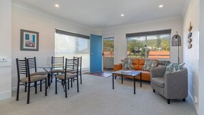 Un salon moderne avec une table à manger en verre, des chaises, un canapé et une table basse.