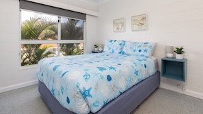 Un dormitorio con cama, ventana, mesita de noche y decoración en la pared.