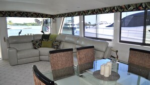 A modern living area with a sofa, wicker chairs, a glass table, and a view of the marina. - TRAVEL THE KEYS OR JUST RELAX AT THE DOCK (Key West)
