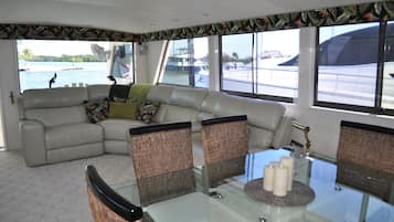 A modern living area with a sofa, wicker chairs, a glass table, and a view of the marina.