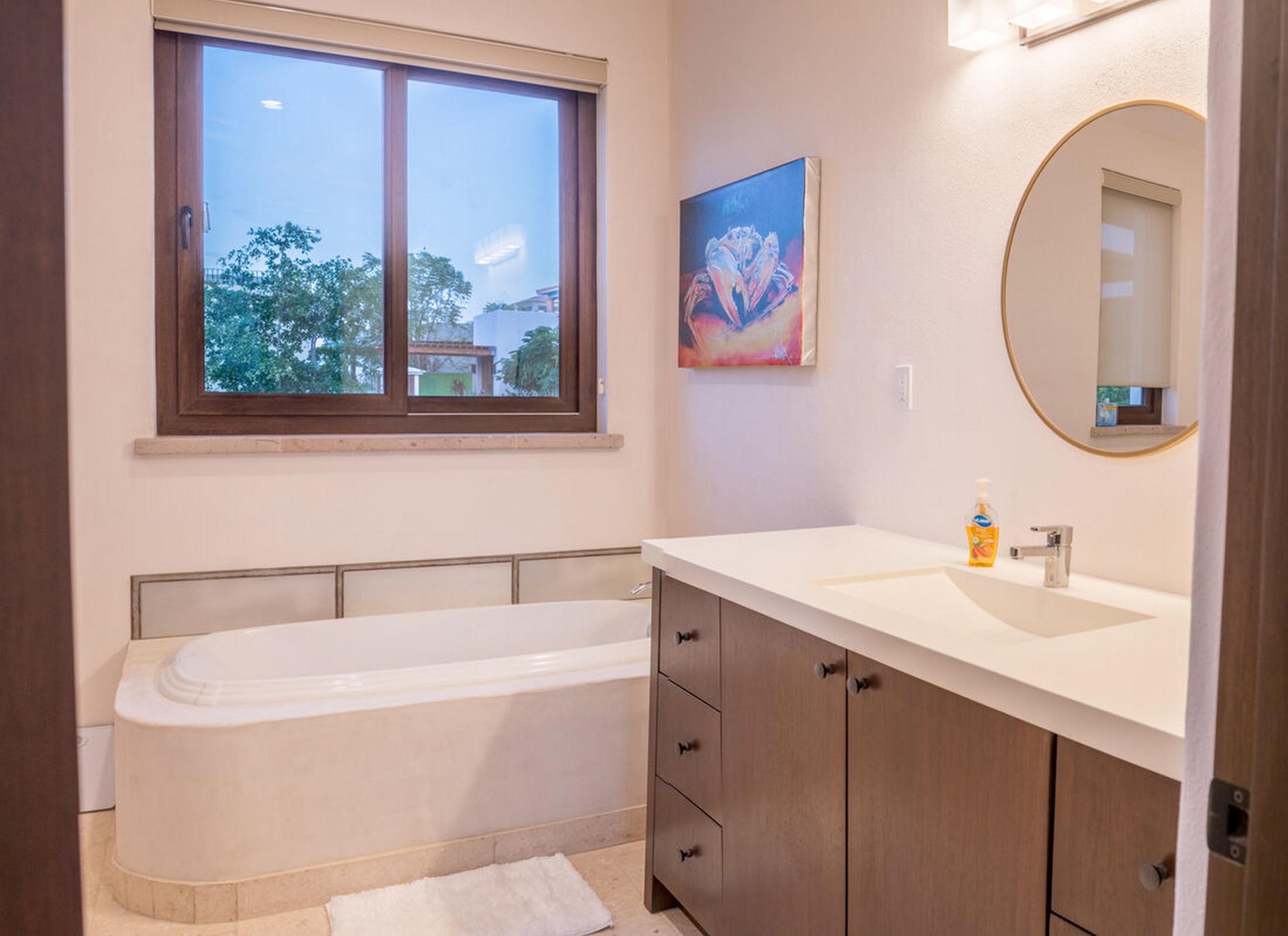 A modern bathroom with a bathtub, a sink, and a large mirror.