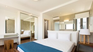 A modern hotel room with a large bed, a wooden stool, a desk with a lamp, and a large mirror. - Modern Villa with Unique Architecture & Captivating Sunsets (Skouloufia)